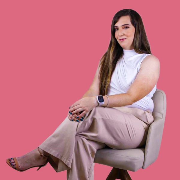 Profissional sorrindo durante videochamada exibida em notebook sobre a mesa.